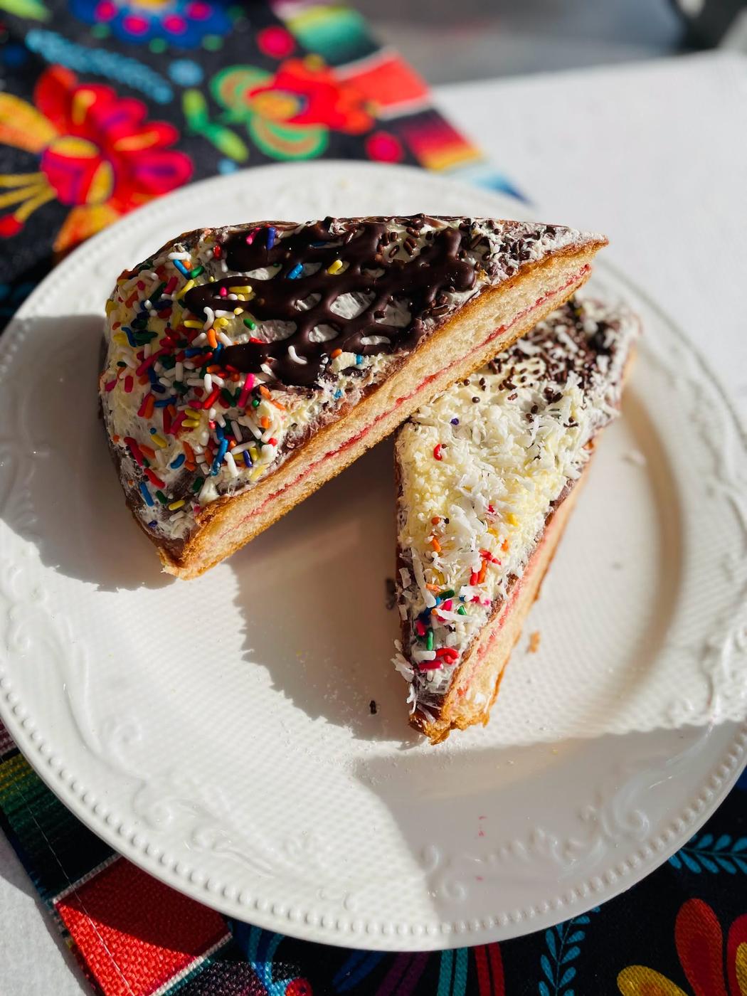 A cut layer cake with sprinkles and chocolate drizzle from Diana's Bakery.